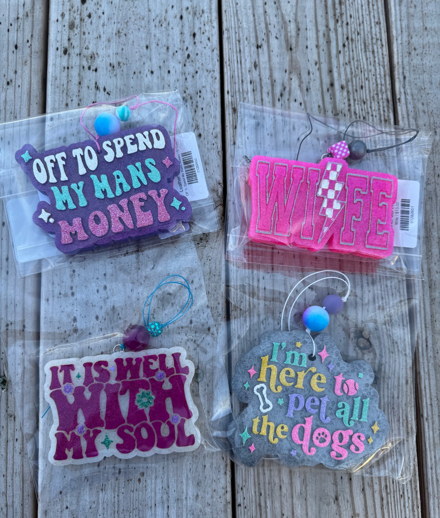 Four colorful keychains with text on a wooden surface