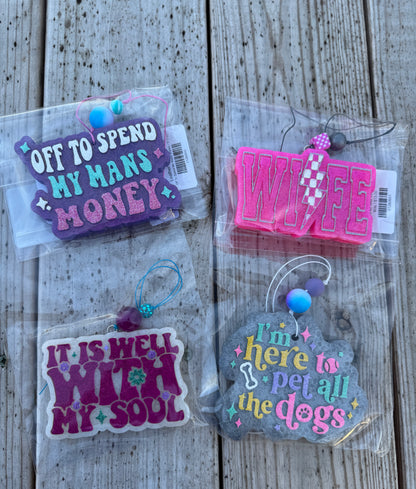 Four colorful keychains with text on a wooden surface