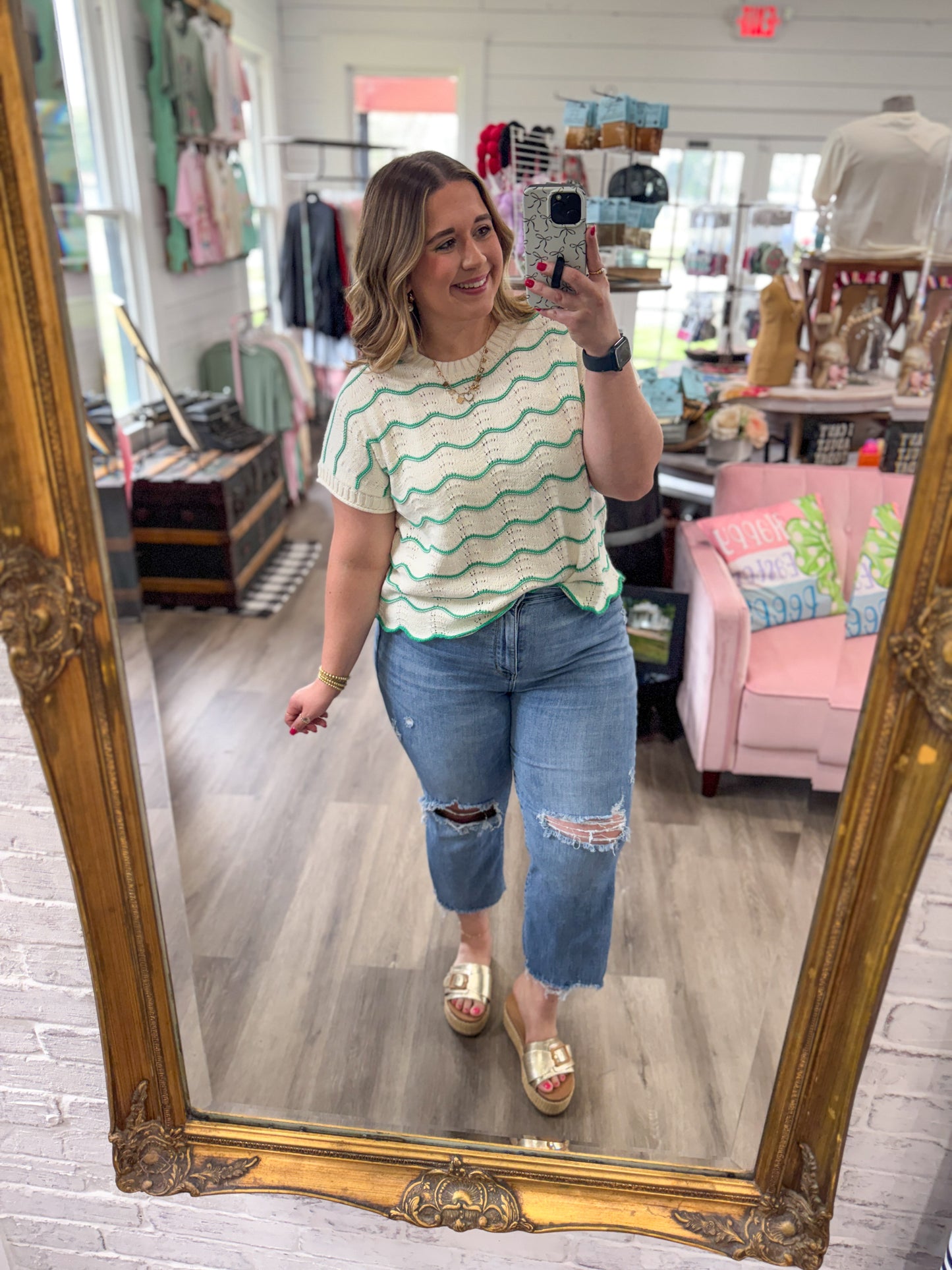 Woman taking a mirror selfie wearing a striped shirt and jeans in a store.