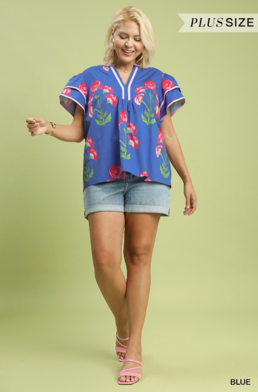 Woman wearing a blue floral blouse and denim shorts on a light green background