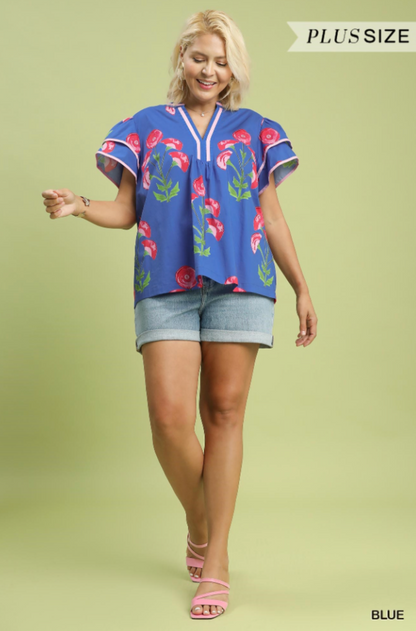 Woman wearing a blue floral blouse and denim shorts on a light green background