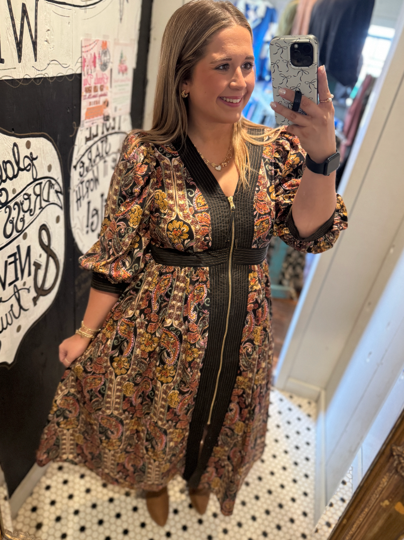 Woman taking a mirror selfie wearing a patterned dress in a store.