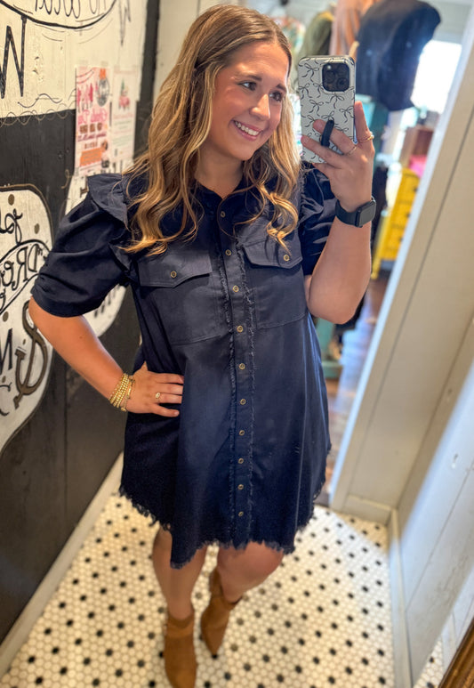 Woman taking a mirror selfie wearing a navy denim dress in an indoor setting.