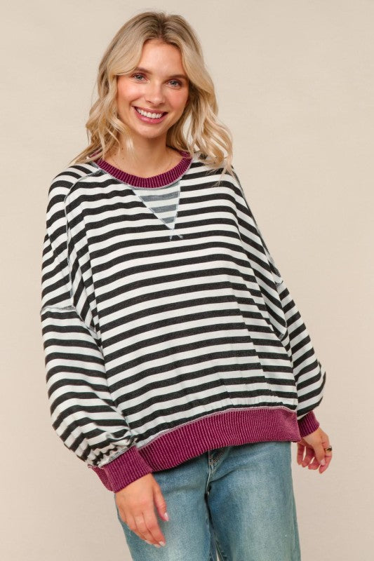 Woman wearing a black and white striped sweater with purple accents on a beige background