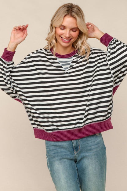 Woman wearing a black and white striped sweater with purple trim on a beige background