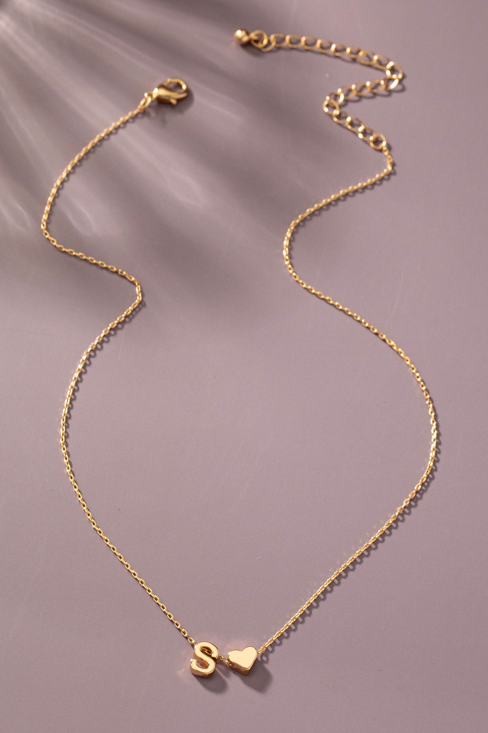 Gold necklace with a heart pendant on a brown background