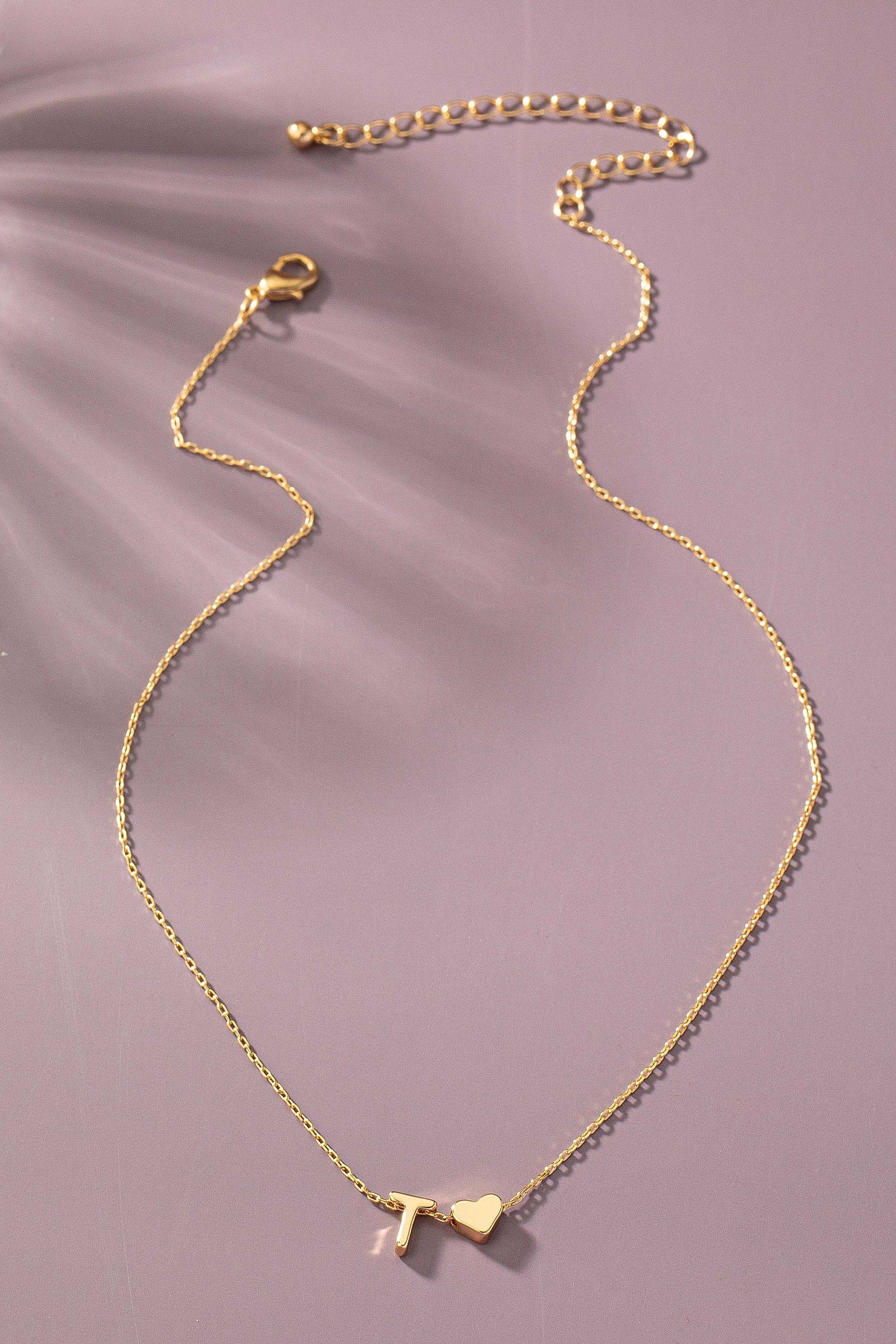 Gold necklace with a heart pendant on a soft purple background