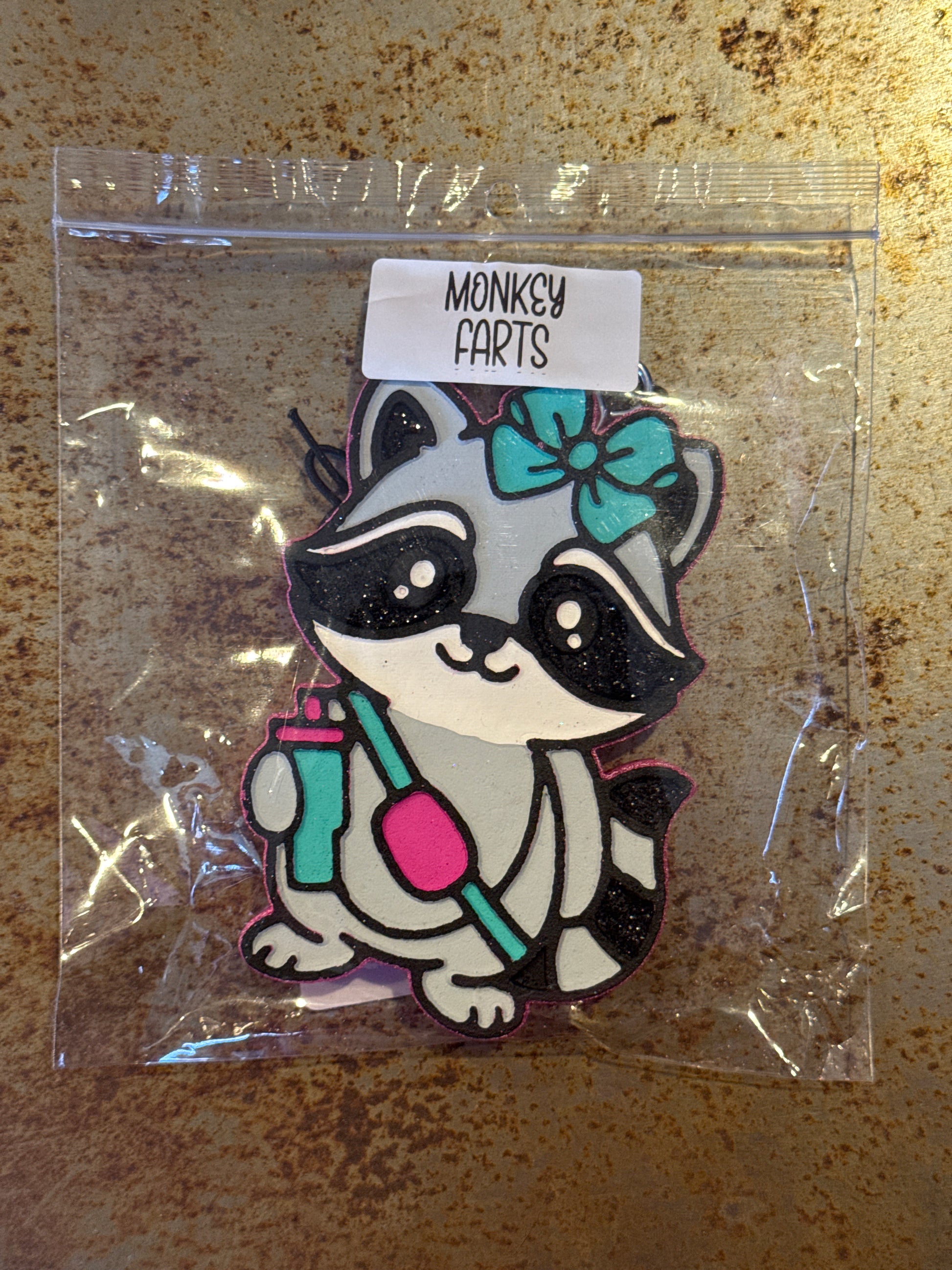 Cartoon raccoon design in clear packaging on a rusty metal surface