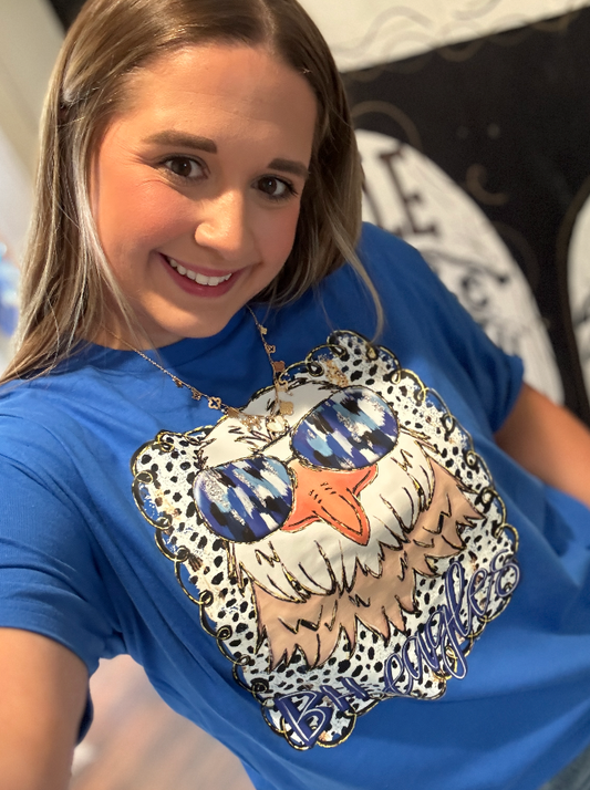 Person wearing a blue t-shirt with a decorative eagle design.