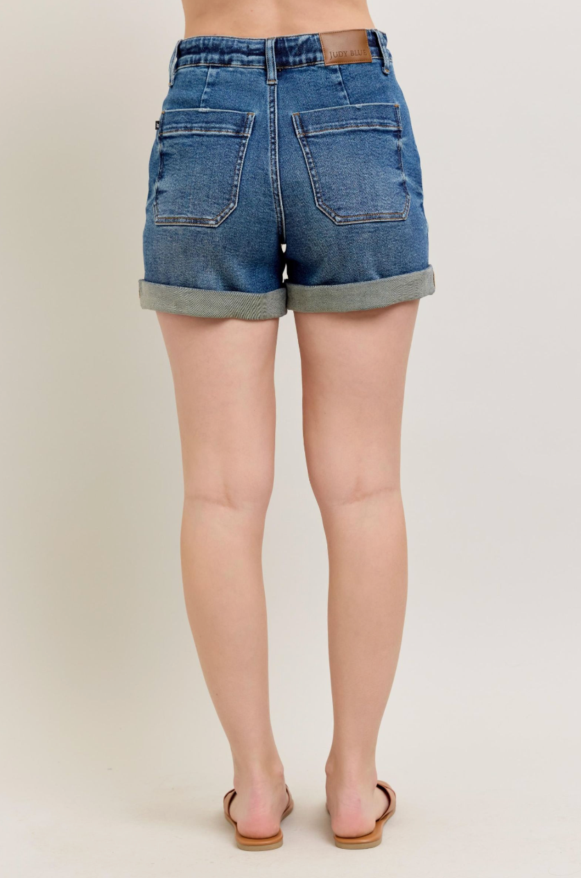 Denim shorts worn by a person on a plain background