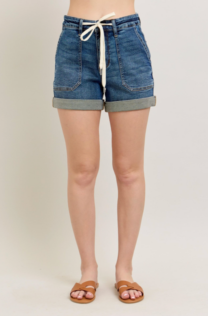 Person wearing blue denim shorts on a plain background