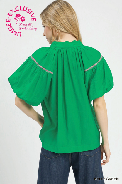 Green blouse with embroidered details worn by a model on a white background
