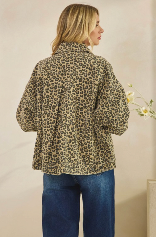 Person wearing a leopard print jacket and blue jeans against a plain background