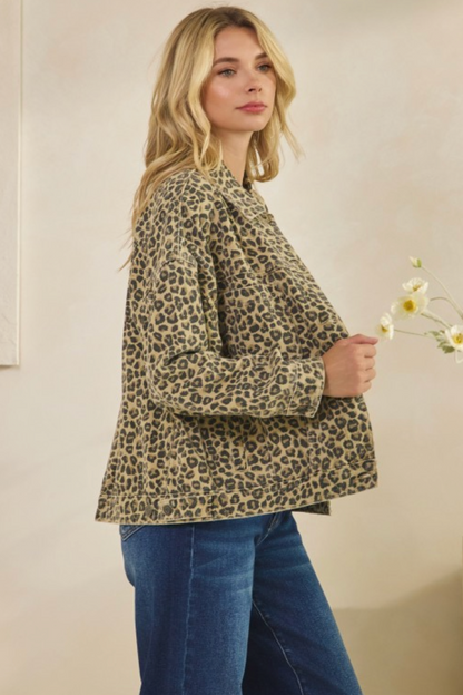 Woman wearing a leopard print jacket and blue jeans, holding flowers against a plain background