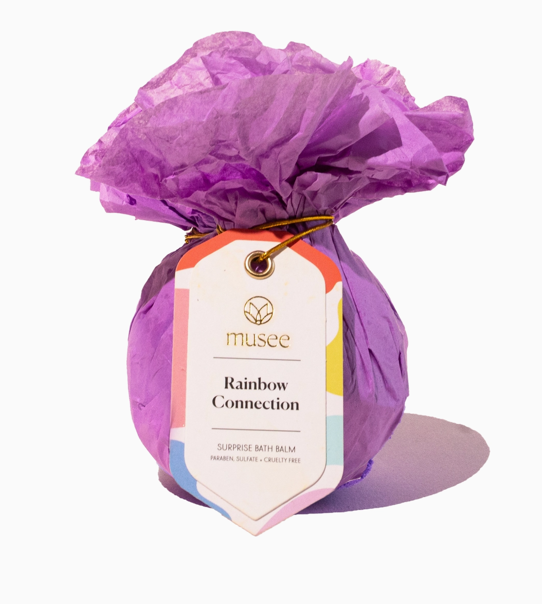Bath balm wrapped in purple tissue paper with a Musee tag on a white background