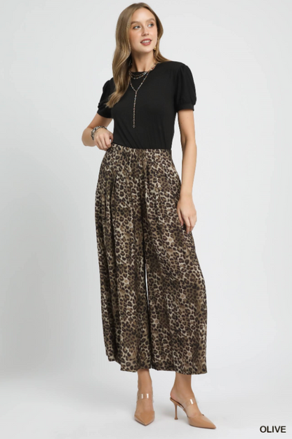 Woman wearing a black top and leopard print skirt on a white background