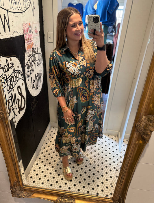 Woman taking a mirror selfie wearing a floral dress in a store.