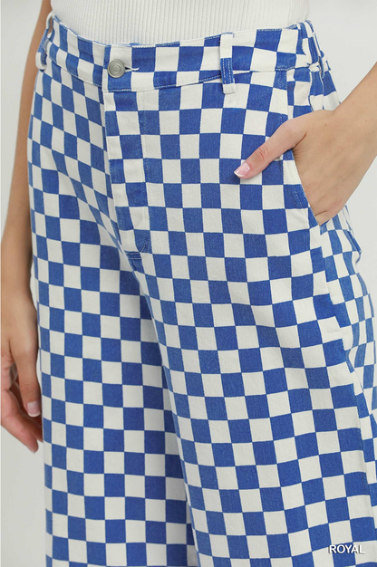 Close-up of a person wearing blue and white checkered pants, with a hand in the pocket and a white ribbed top visible at the waist.