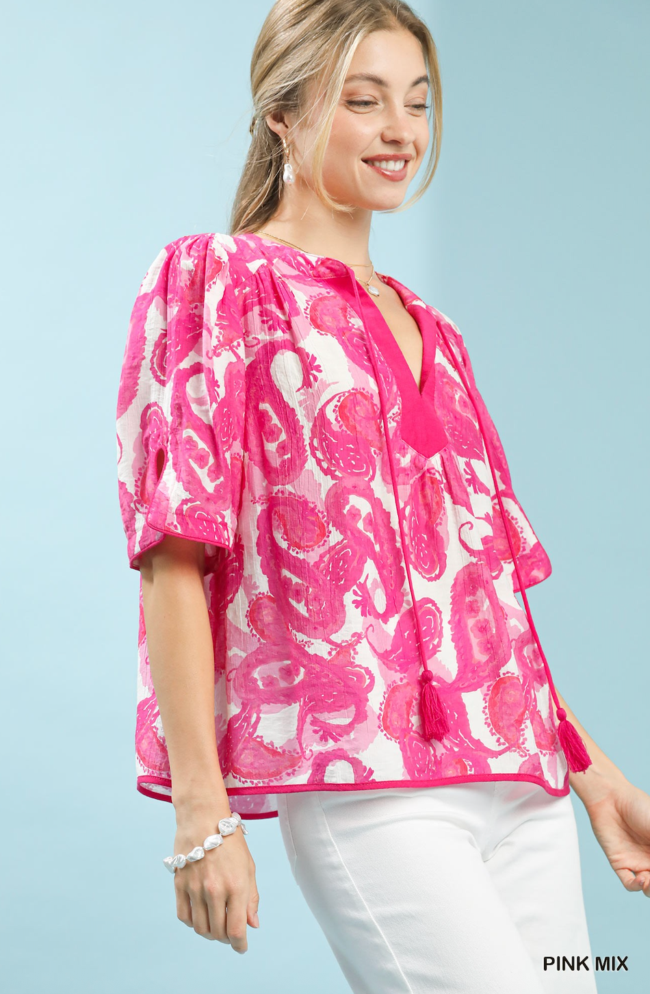 Woman wearing a pink and white patterned blouse against a light blue background