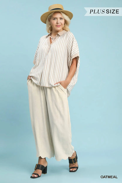 Woman wearing a striped blouse and wide-leg pants with a straw hat on a light blue background.