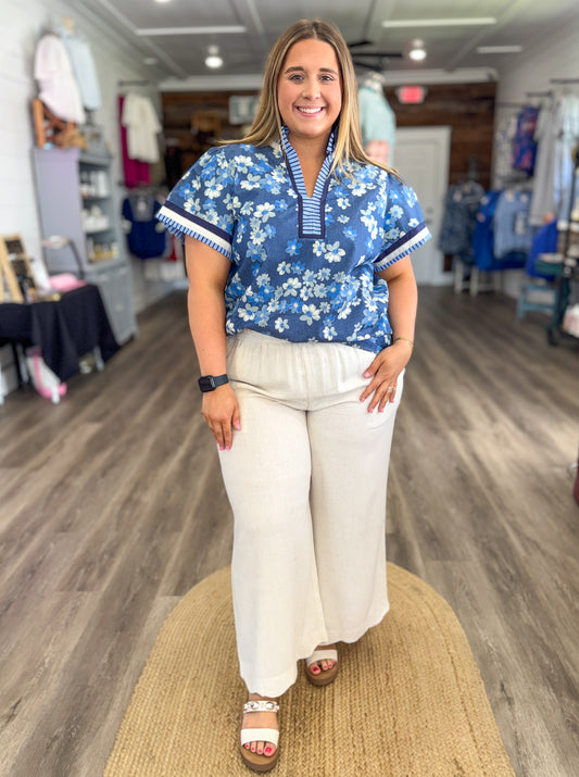 Woman wearing a blue floral blouse and white pants in a store setting