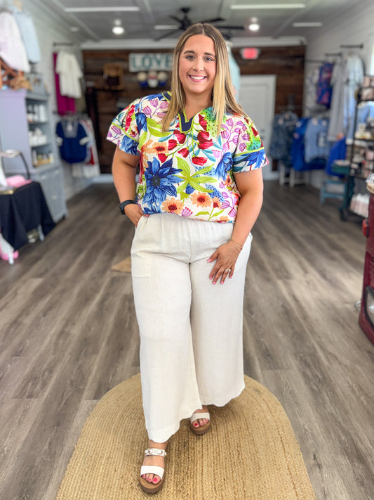 Woman wearing a colorful floral shirt and white pants in a store setting