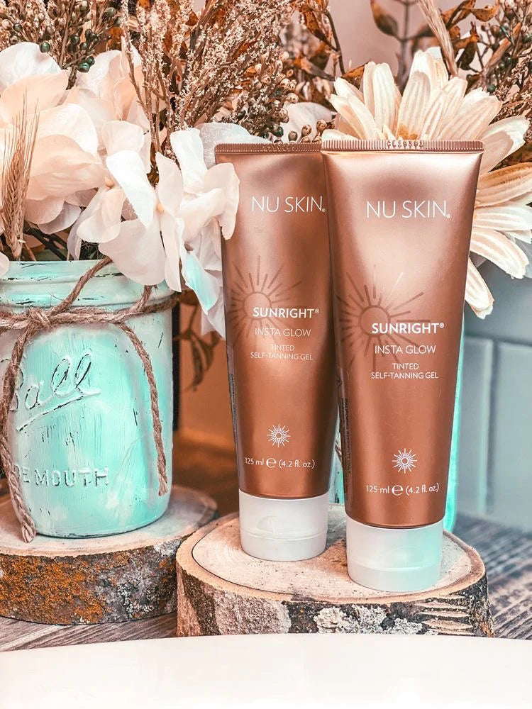 Two NU SKIN Sunlight Self-Tanners on a wooden block with decorative flowers in the background.
