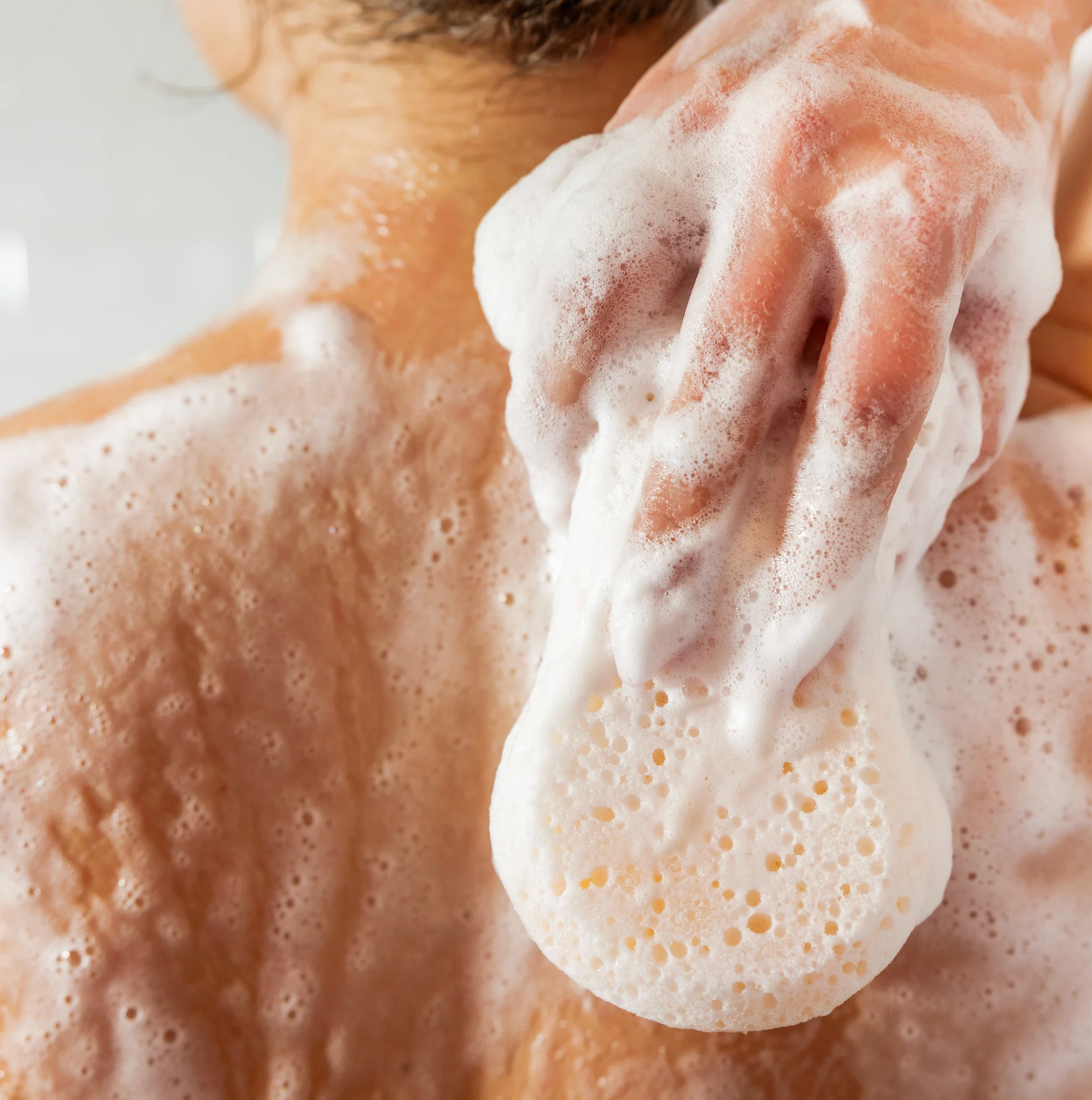 Person applying soap to their skin with a soapy hand