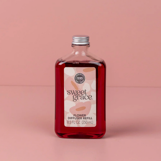 Bottle of 'sweet grace' flower diffuser refill on a pink background