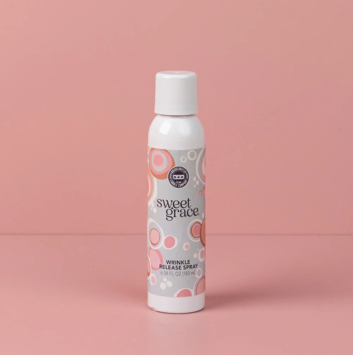 White bottle of 'sweet grace' wrinkle release spray on a pink background