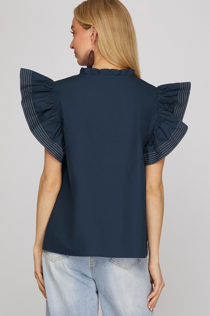 Navy blue blouse with ruffled sleeves worn by a person on a light gray background