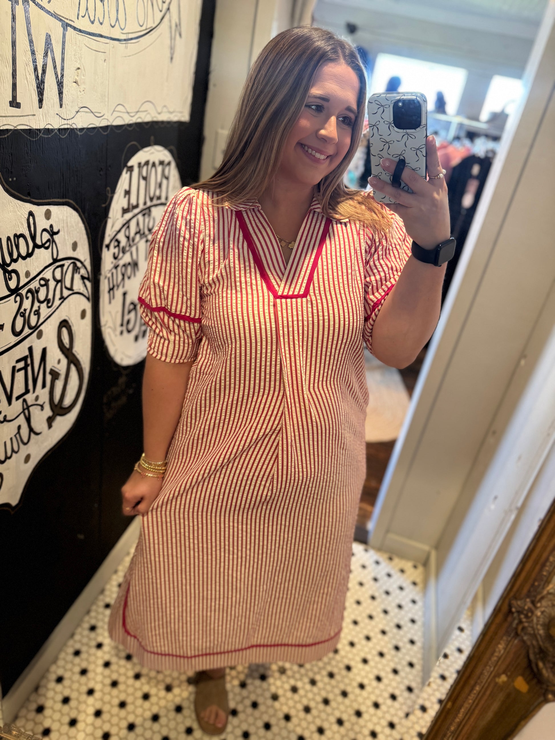 Woman taking a mirror selfie wearing a red and white striped dress.