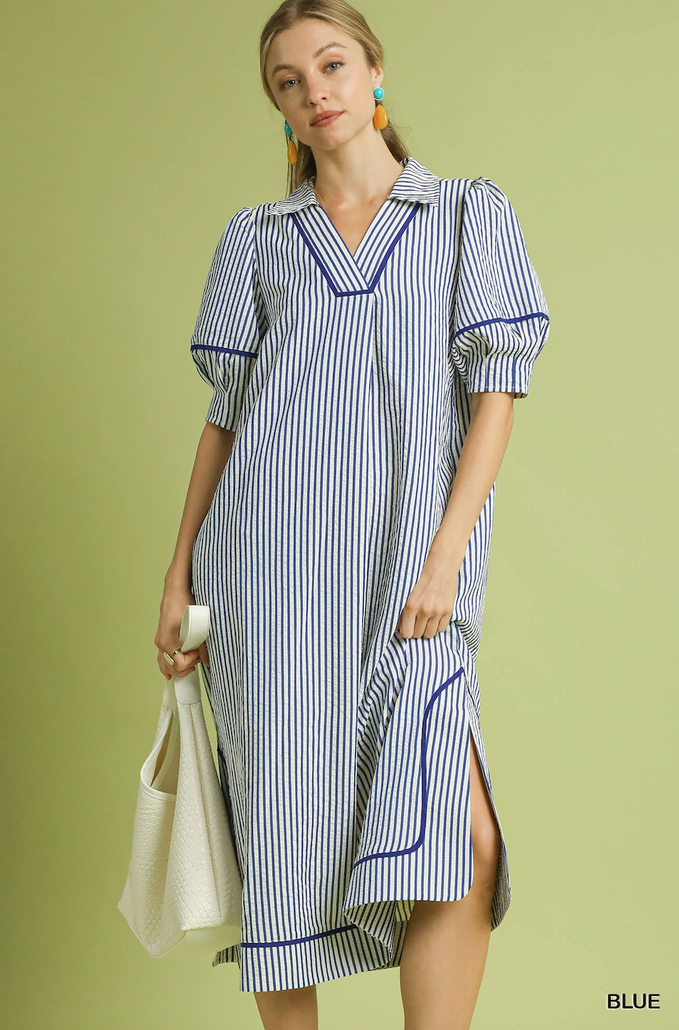 Woman wearing a blue and white striped dress on a green background