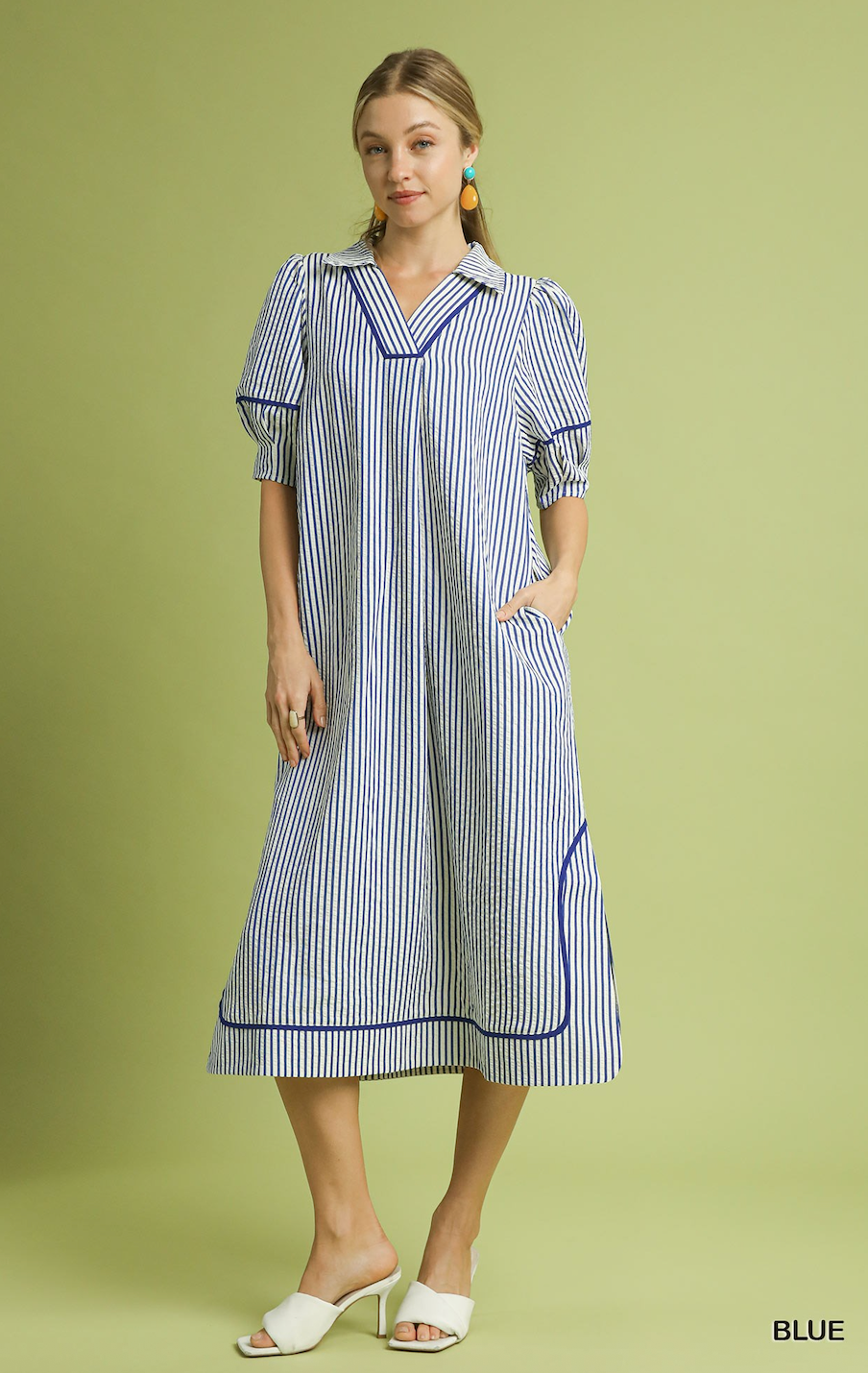 Woman wearing a blue and white striped dress on a green background