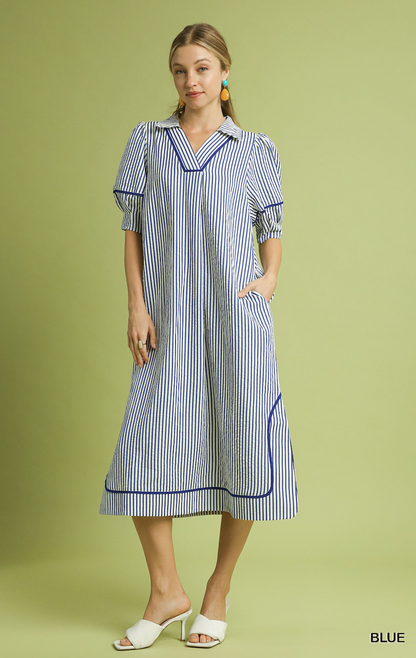 Woman wearing a blue and white striped dress on a green background