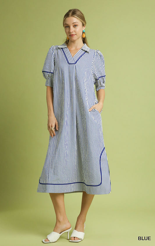 Woman wearing a blue and white striped dress on a green background