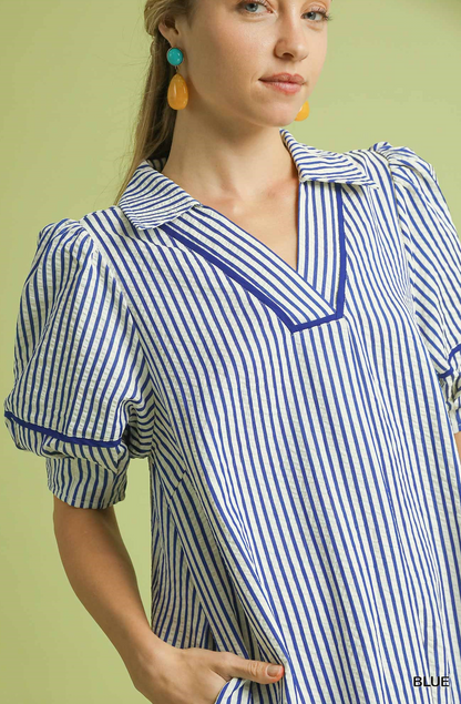 Woman wearing a blue and white striped dress with a plain background