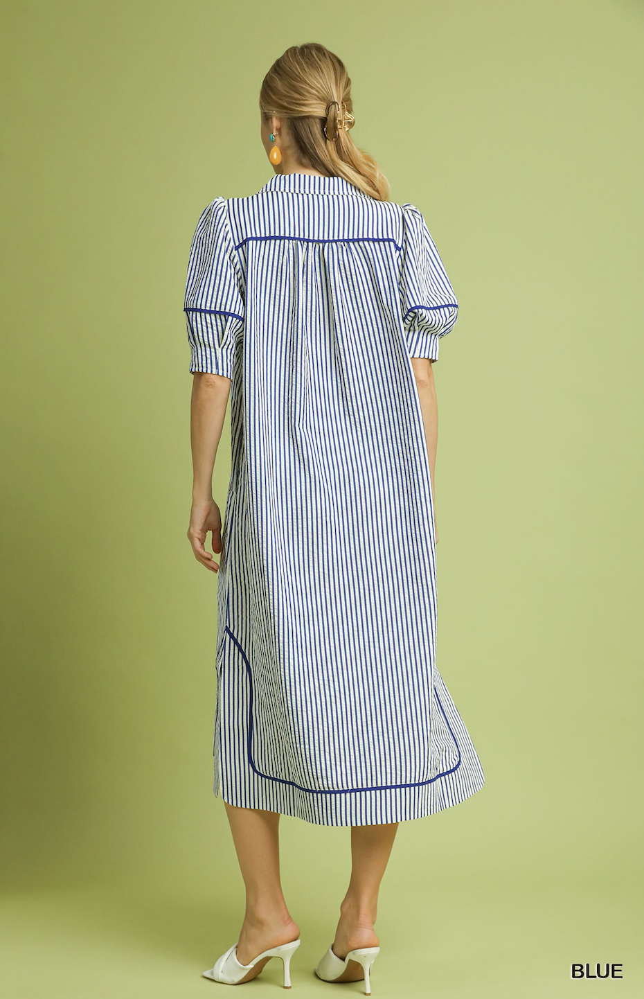Woman wearing a blue and white striped dress on a green background