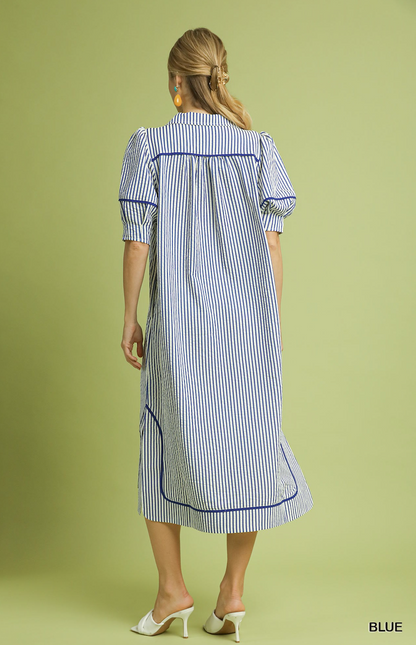 Woman wearing a blue and white striped dress on a green background