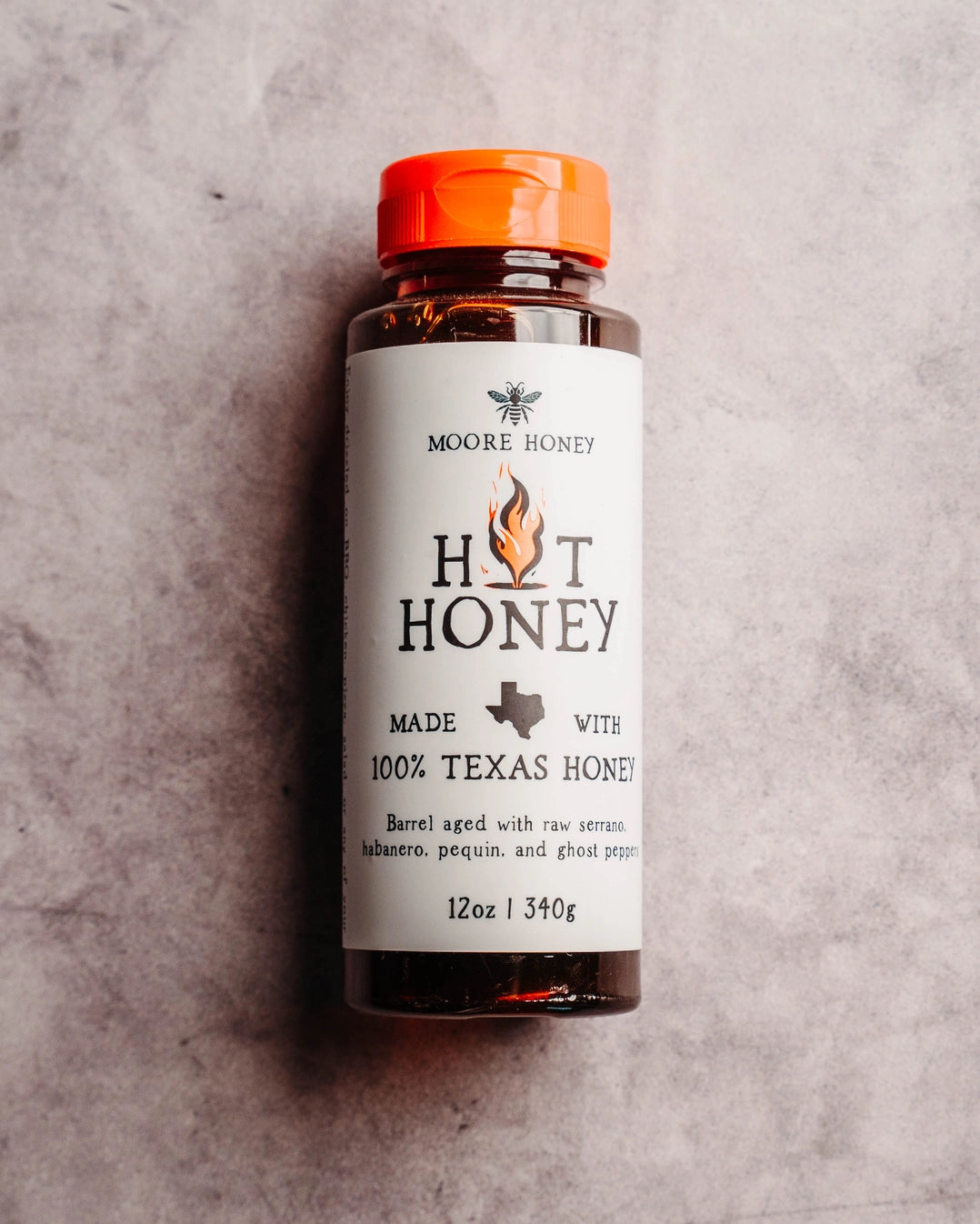 Bottle of Moore Honey Hot Honey on a textured gray background