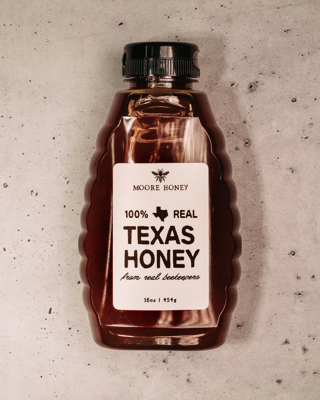 Bottle of Moore Honey with a label on a textured surface