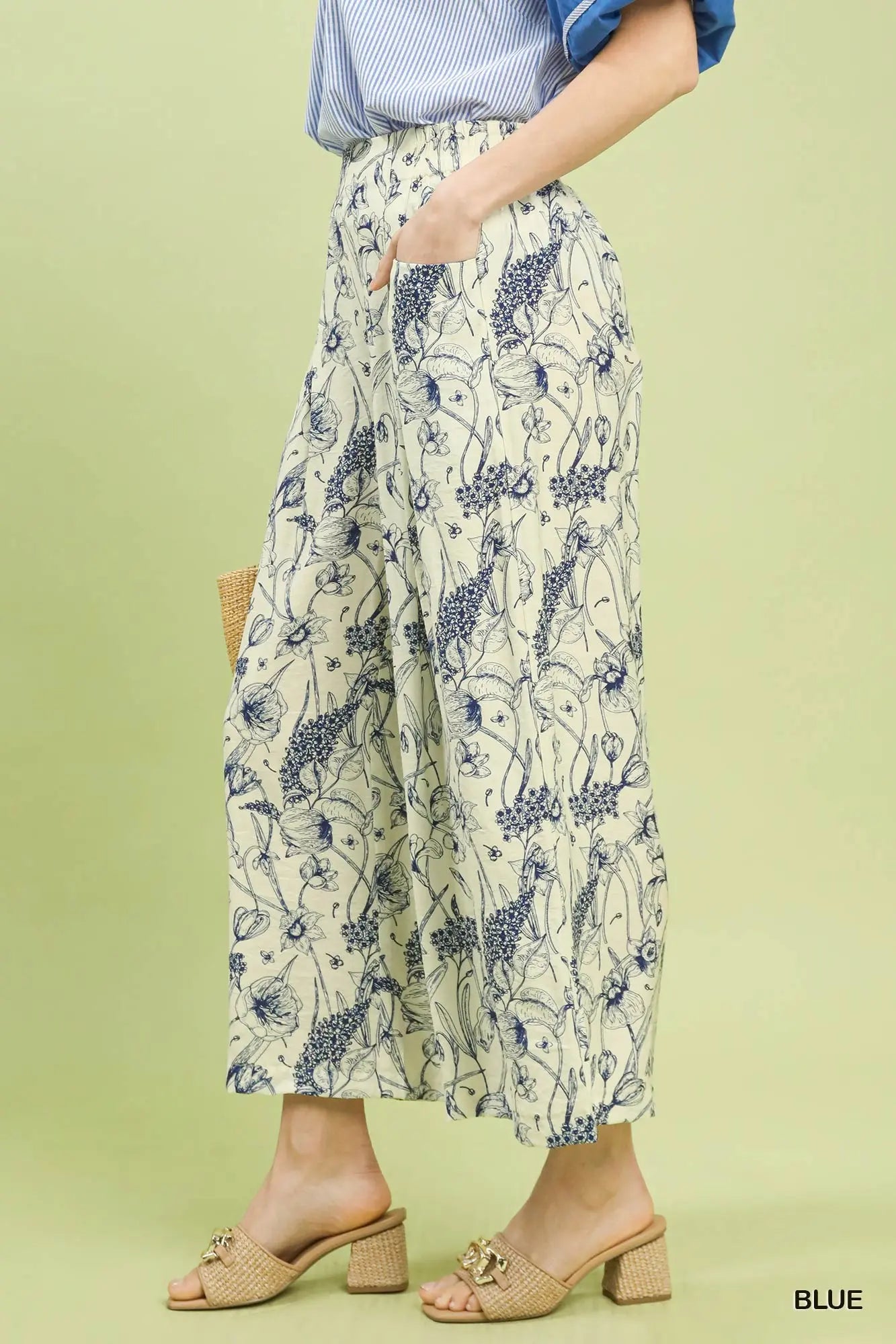 Person wearing floral-patterned pants on a light green background