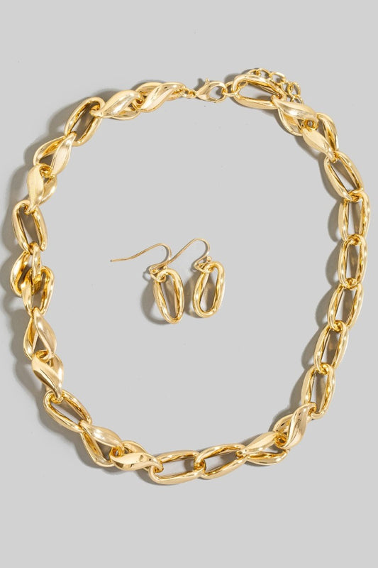 Gold chain necklace and earrings on a gray background