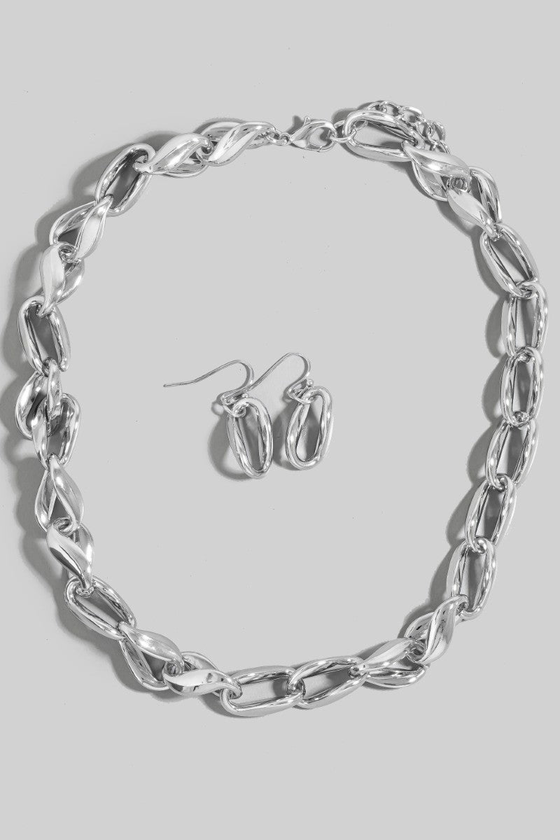 Silver chain necklace and hoop earrings on a gray background