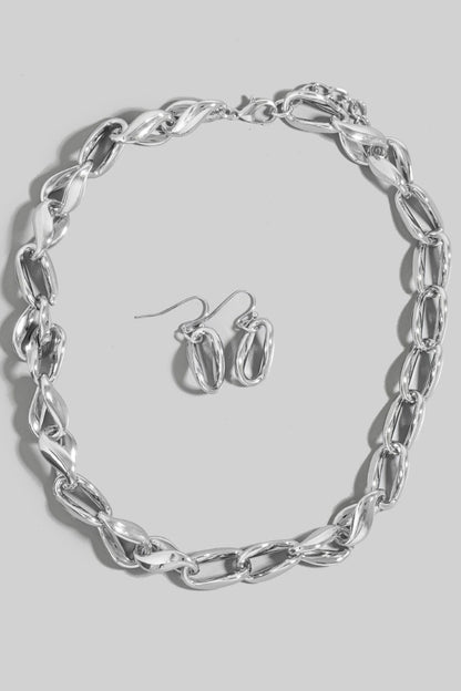 Silver chain necklace and hoop earrings on a gray background