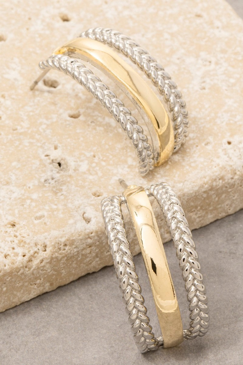 Two gold and silver bracelets on a textured stone surface
