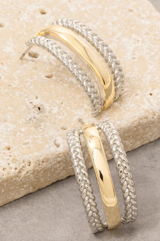 Two gold and silver bracelets on a textured stone surface