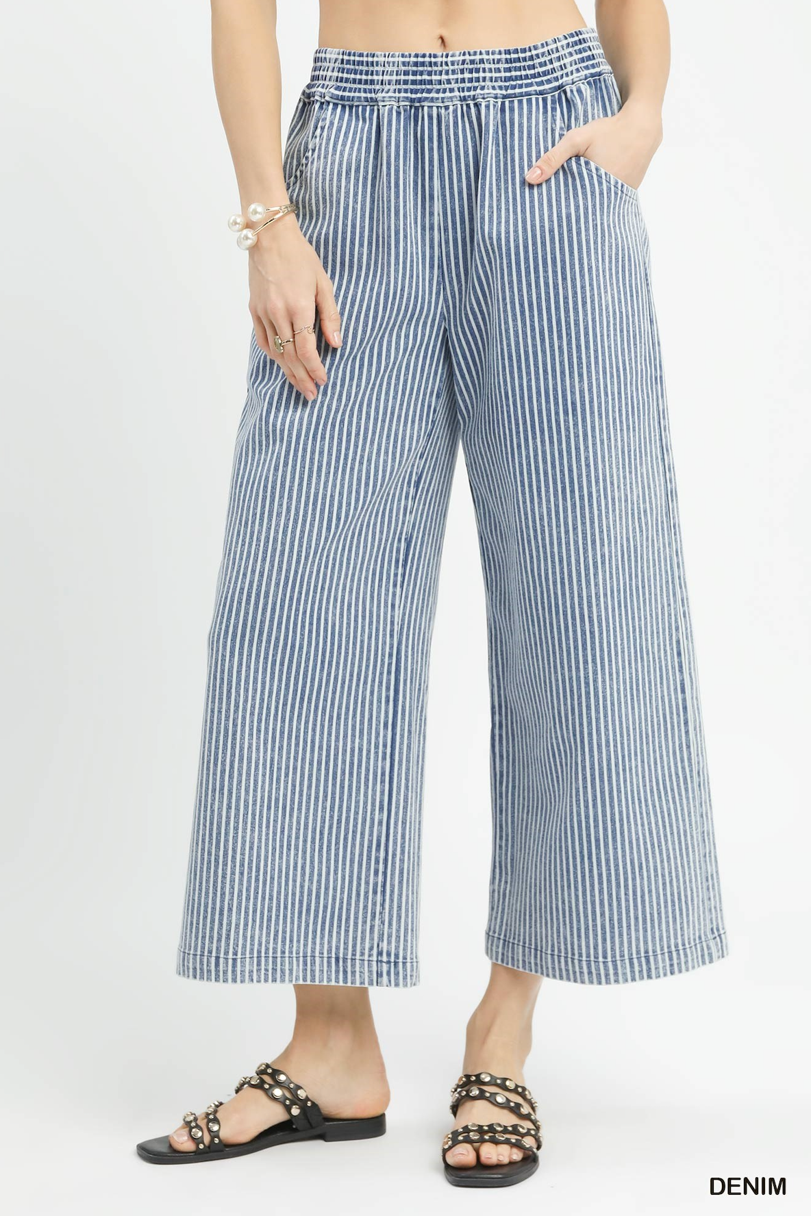 Person wearing blue and white striped wide-leg pants on a light gray background