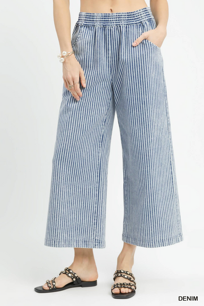 Person wearing blue and white striped wide-leg pants on a light gray background