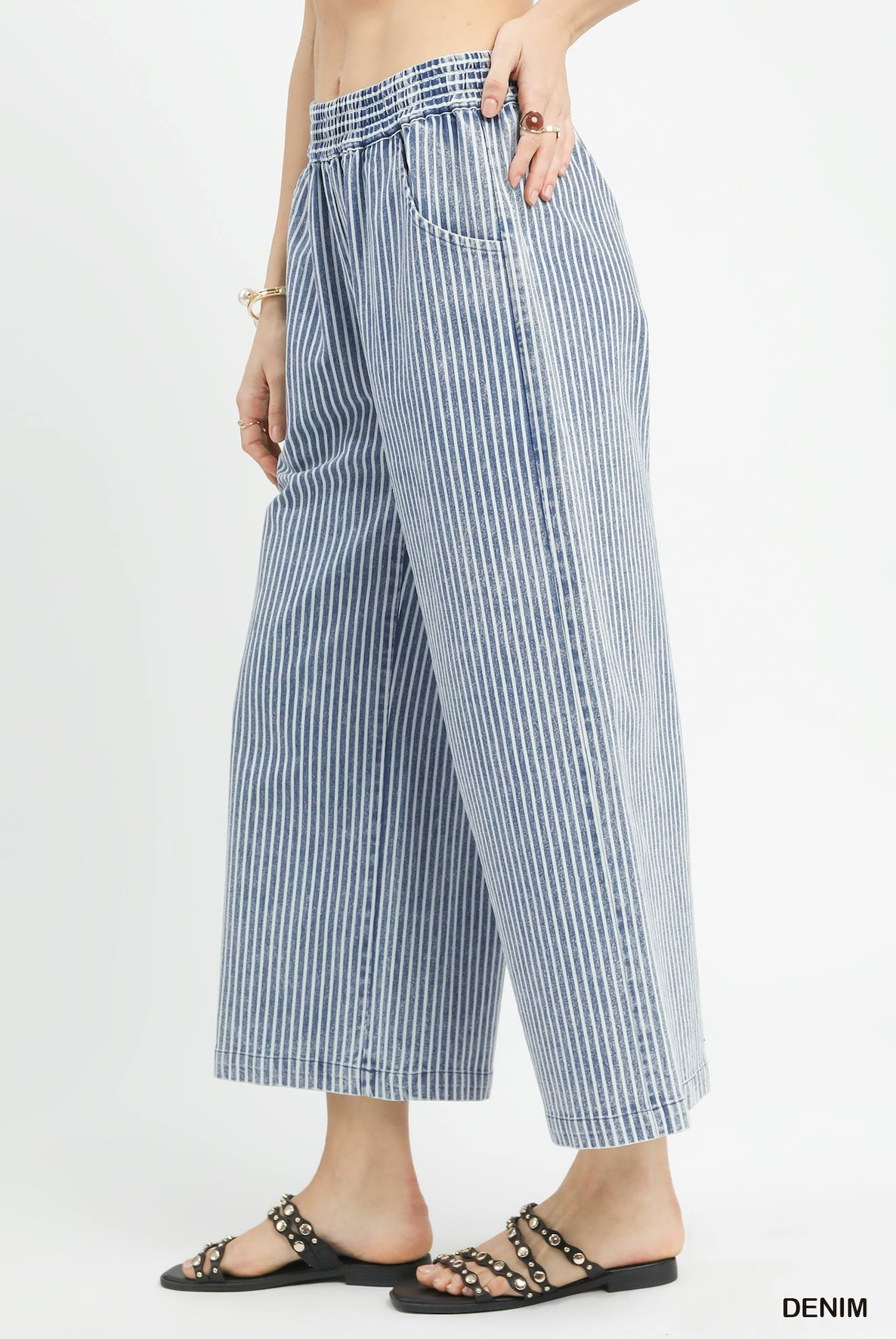 Blue and white striped pants worn by a person on a light gray background